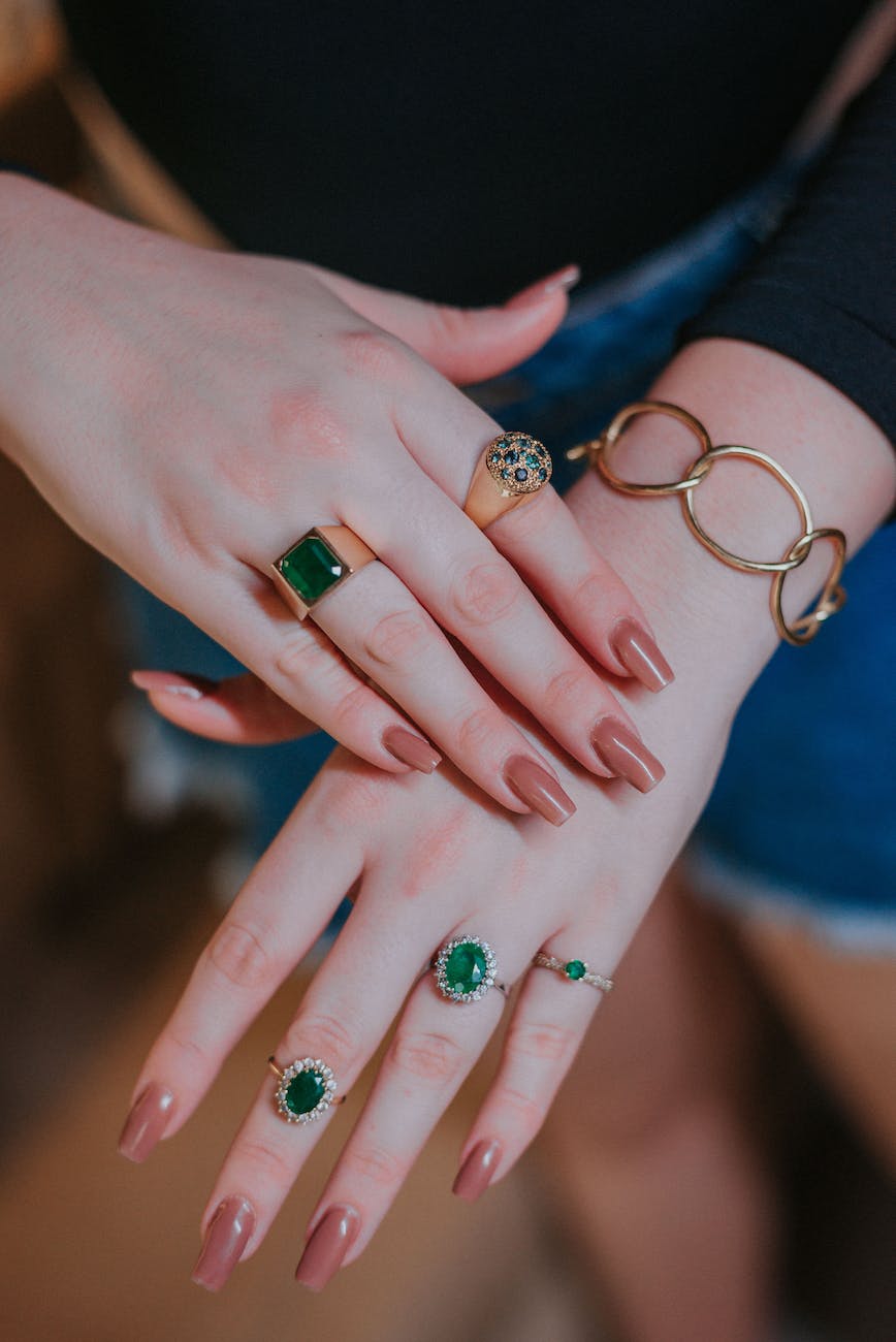 person wearing gold rings with emerald